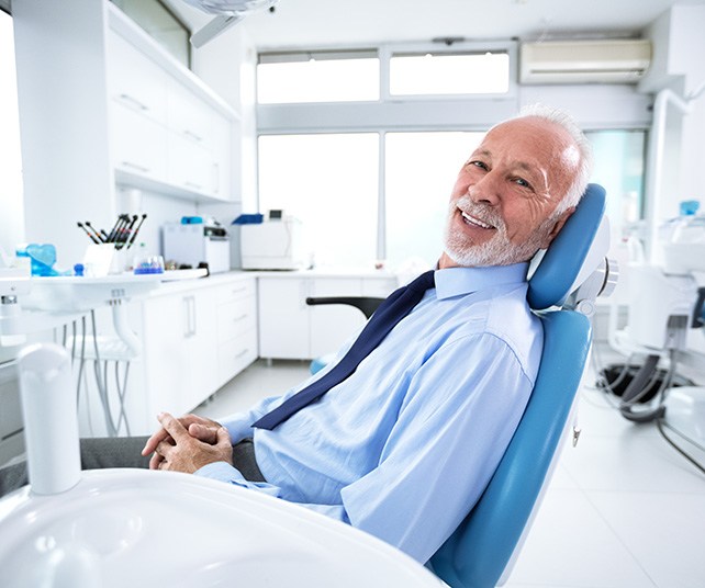 Man leaning back in dental chair and smiling