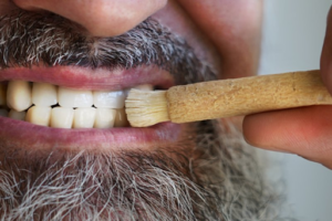 Close up of man using an ancient toothbrush on his teeth